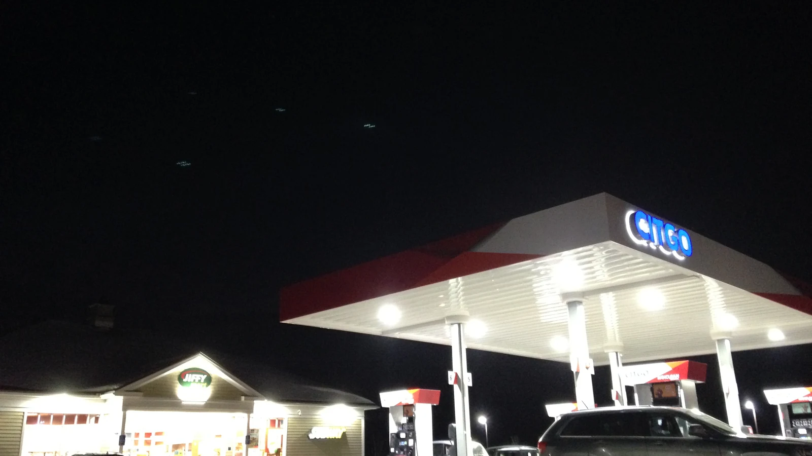 Night photo of a gas station canopy and pumps for a warehouse-club fuel savings guide.